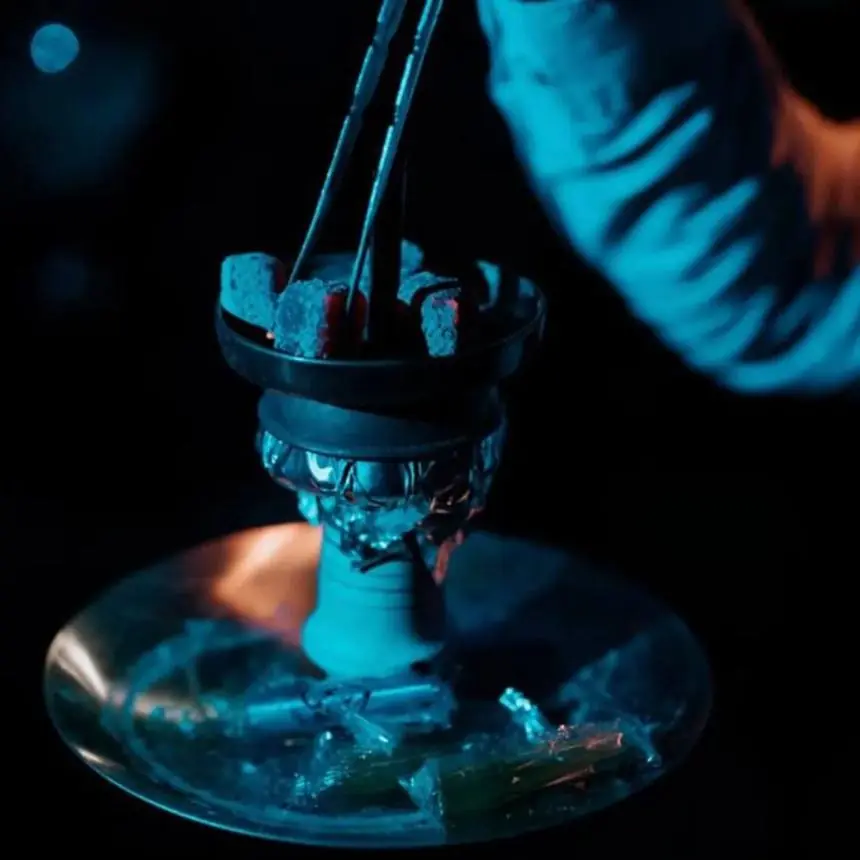Carbón 100% coco colocado con pinzas sobre el hornillo de una hookah Cyril