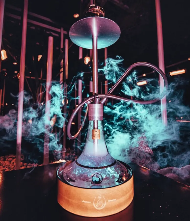 Hookah premium envuelta en humo turquesa en terraza nocturna