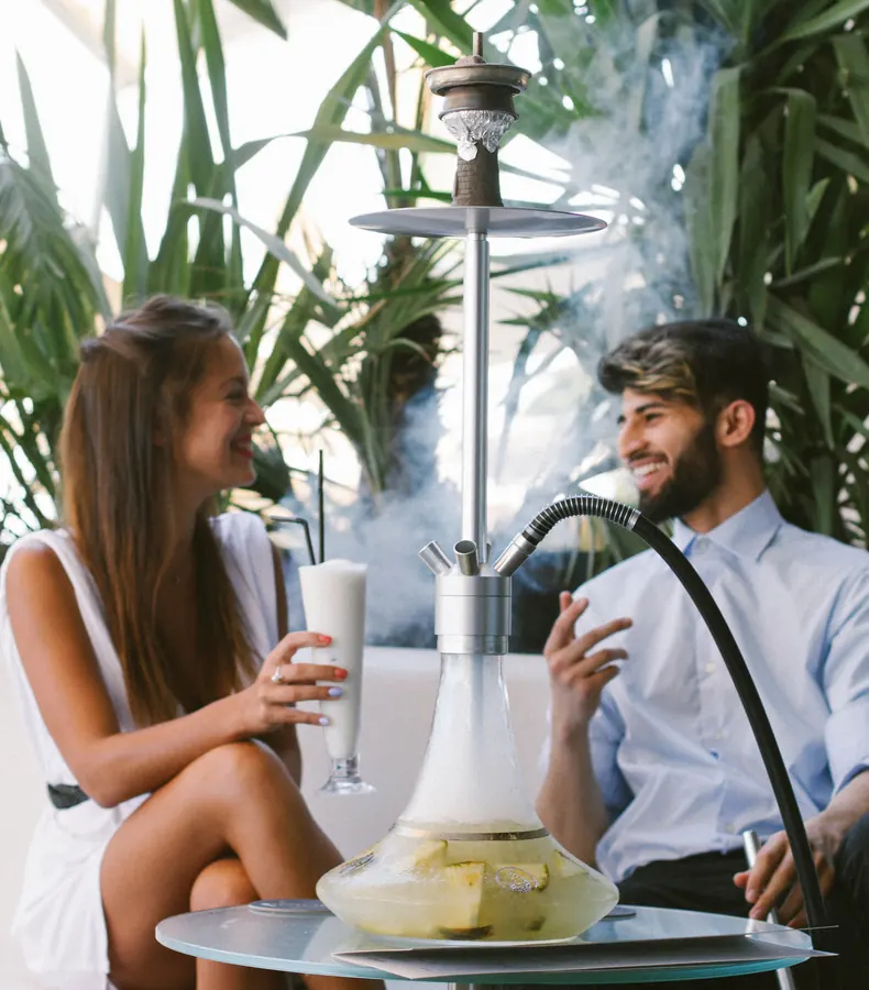 Pareja disfrutando una hookah Cyril en terraza con vegetación