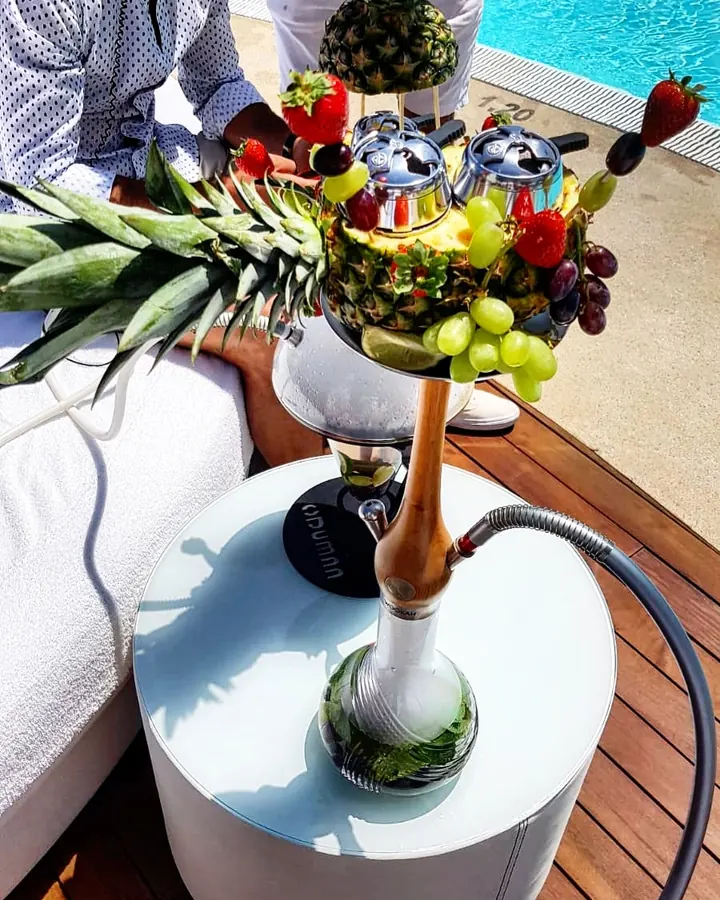 Hookah de piña con frutas frente a la alberca de un hotel