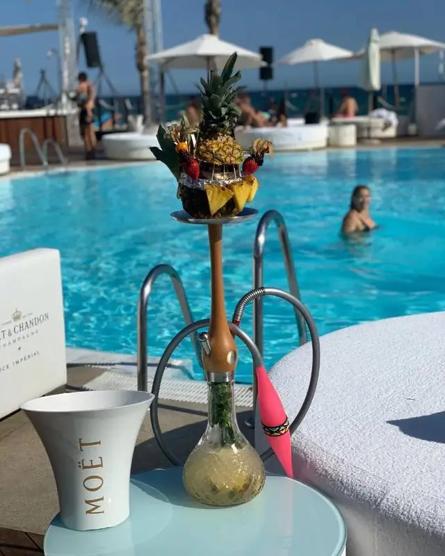 Hookah de piña junto a la alberca de un beach club